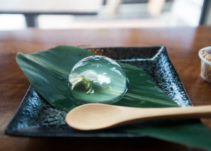 Wunderschöner japanischer Regentropfen-Kuchen auf einem Blatt, mit einer Blume in einer süßen und erfrischenden Kugel aus Gelatine-Dessert